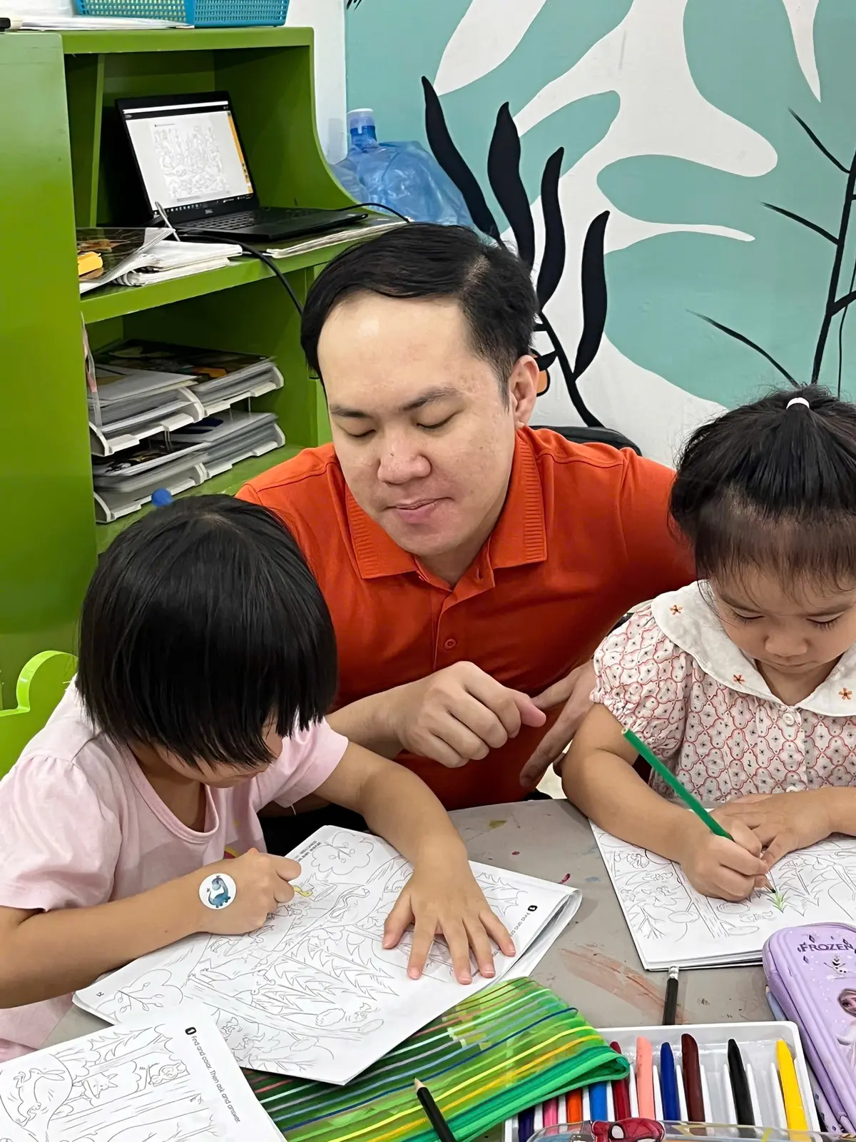 Thầy giáo hướng dẫn hai bạn nhỏ tô màu